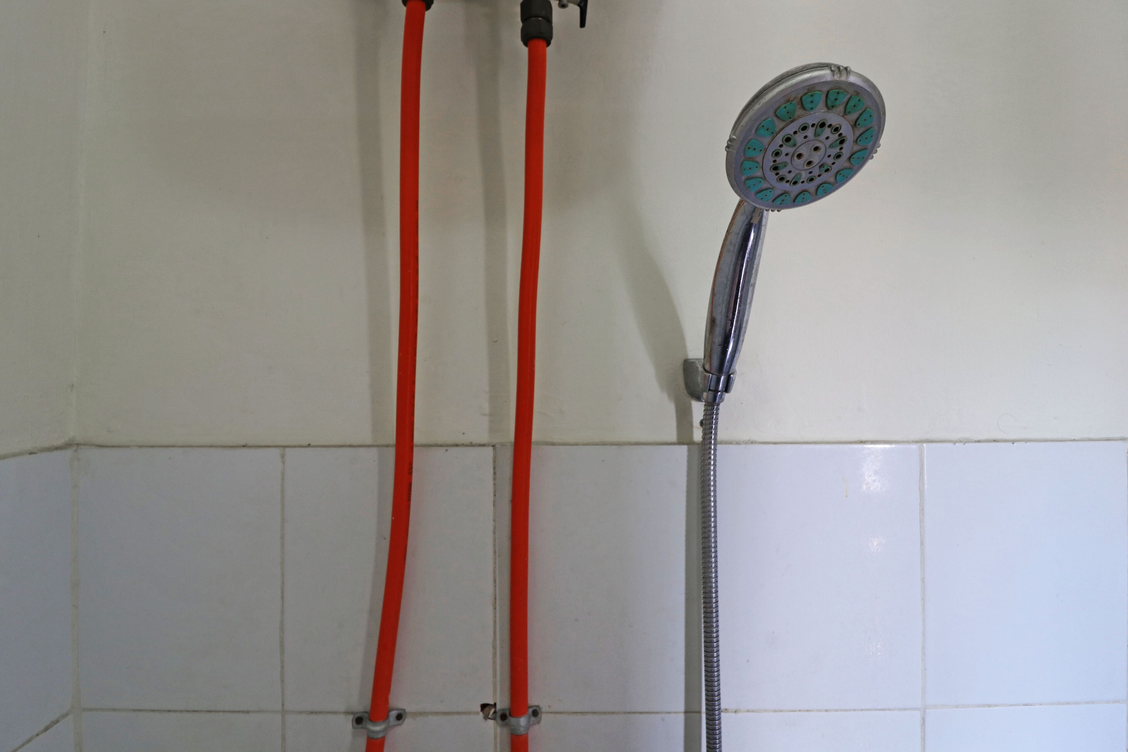 Ducha con dos mangueras rojas y un cabezal plateado.