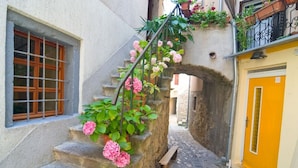 A narrow stone staircase with pink flowers, a wooden bench, and a yellow door. - Studio apartment in Baška with Seaview, Balcony, Air condition, WIFI (3494-2) (Baška)