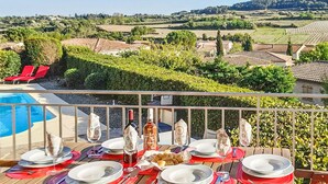 A dining table set outdoors with a view of vineyards and houses in the background.