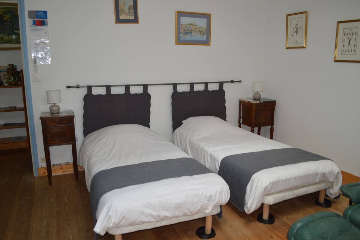 Una cama doble con cabecera de madera, una mesita de noche con lámpara y una silla verde.