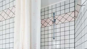 Un área de ducha con puerta de vidrio, ducha y panel de control.