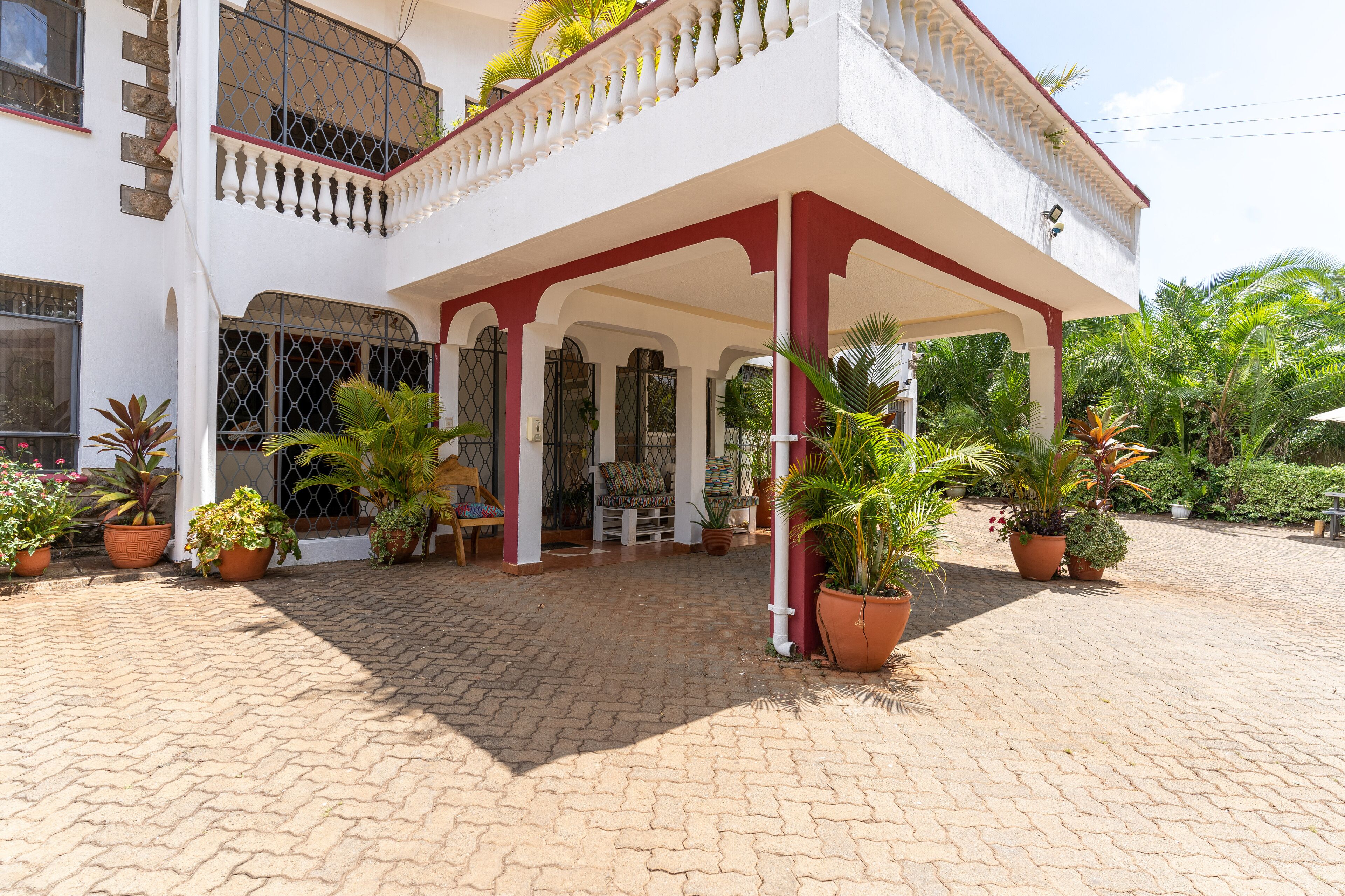 A two-story building with a covered entrance, potted plants, and a brick-paved area.