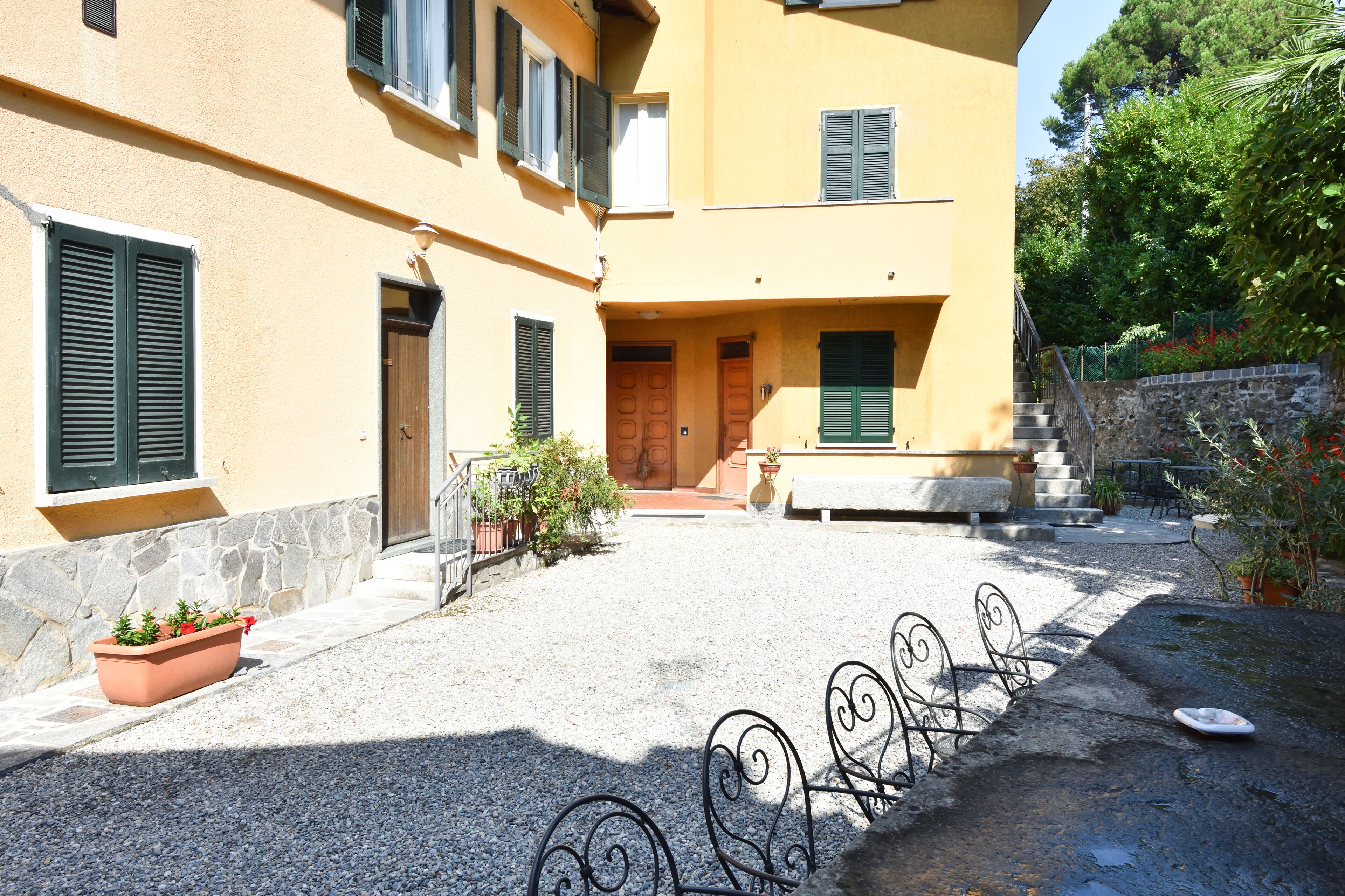 A courtyard with a stone wall, a wooden door, and a bench.