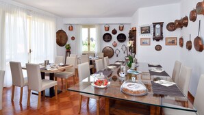 A dining area with a glass table, chairs, and a variety of copper cookware displayed on the wall.