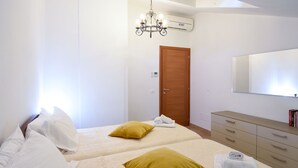 A bedroom with two beds, a wooden door, a mirror, and a dresser.