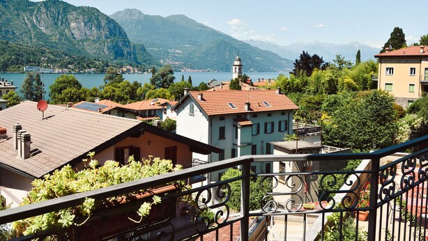 A residential area with buildings, a mountain backdrop, and a lake.