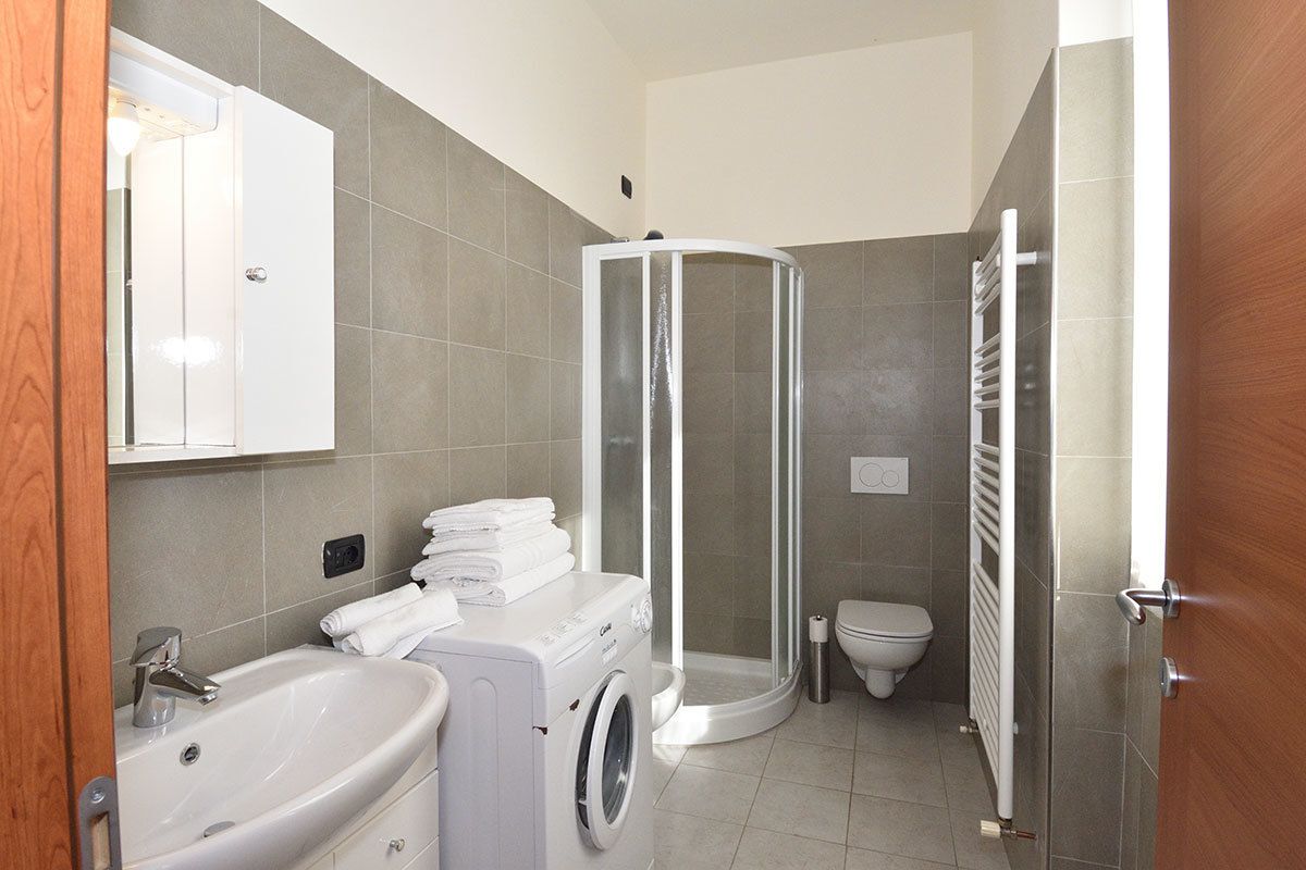 A compact bathroom with a shower enclosure, a sink, and a washing machine.