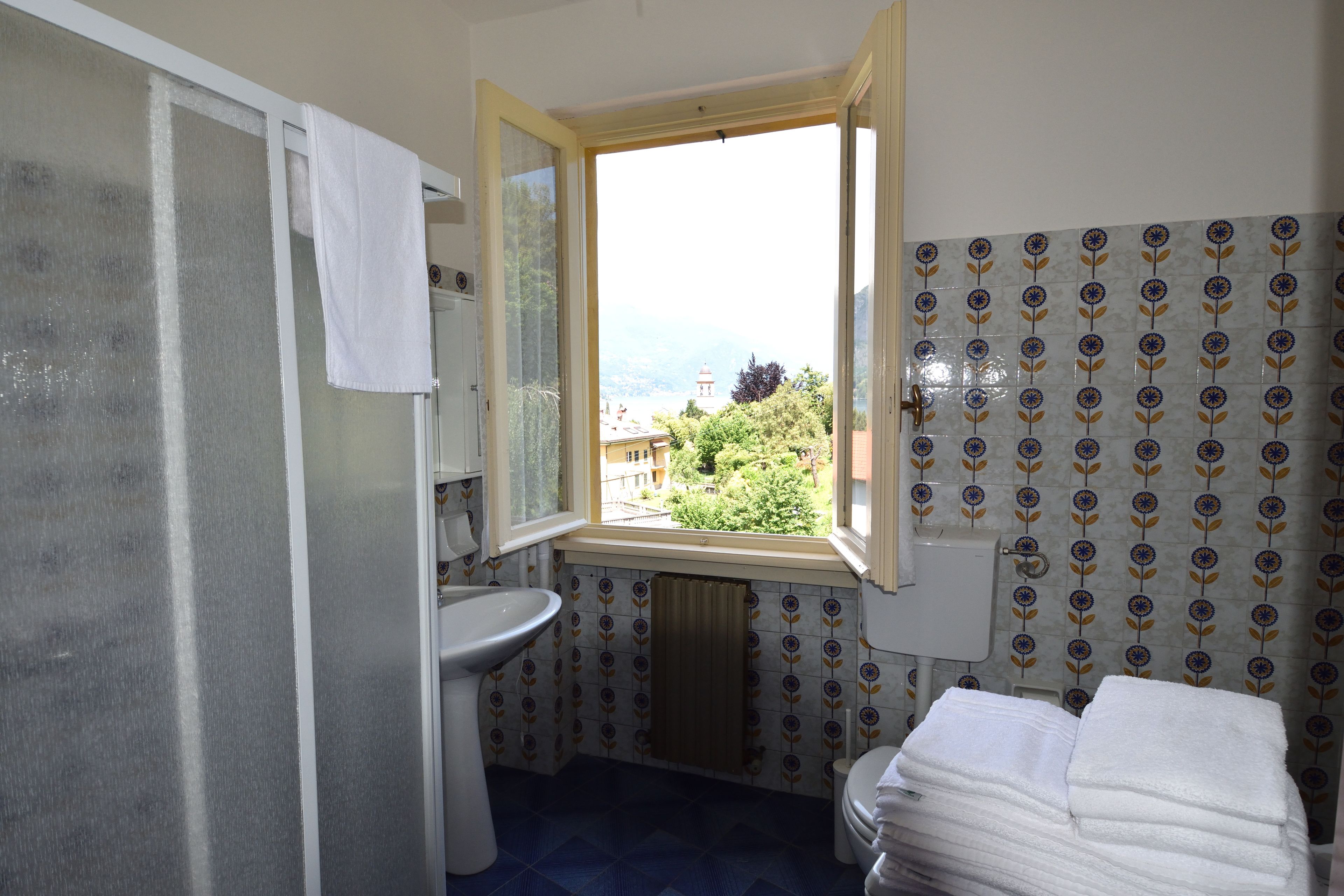A bathroom with a window, a sink, a toilet, and a towel rack.