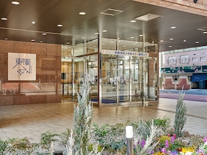 A hotel entrance with a glass door, a signboard with Japanese characters, and a tiled floor.