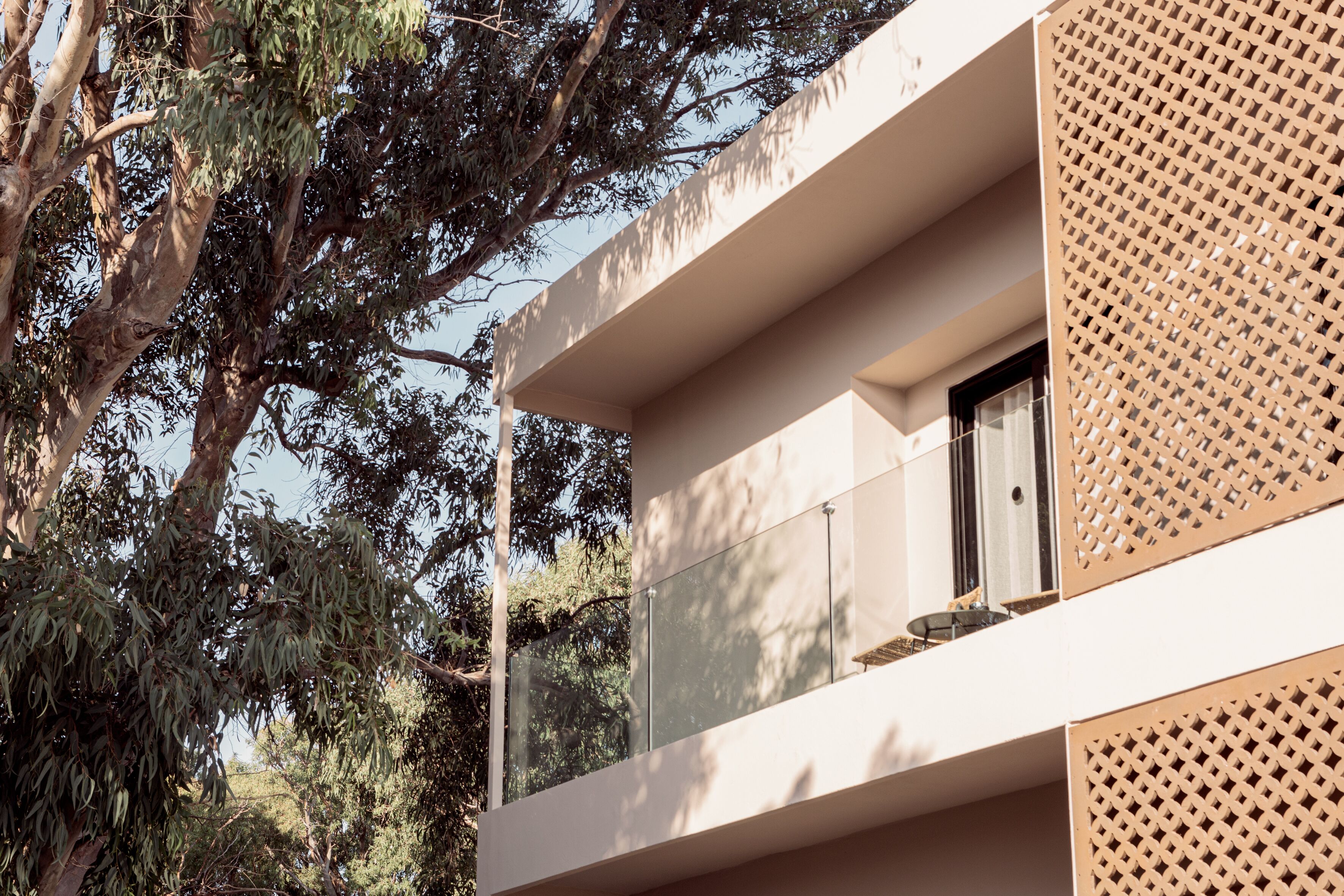 Un edificio moderno con balcón, ventanas amplias y un diseño de celosía en la fachada.