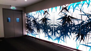 A hallway with a wall featuring abstract bamboo art and a door with an emergency exit sign. - QUAD 3 Apartment with Balcony, Air Conditioned, Garage, City view, 24/7 security (Lisbon)
