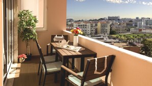 A balcony with a wooden table, chairs, a potted plant, and a vase of flowers. - QUAD 3 Apartment with Balcony, Air Conditioned, Garage, City view, 24/7 security (Lisbon)