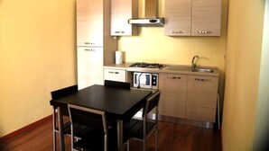 A compact kitchen with a gas stove, microwave, and a sink. There is a small dining table with chairs.