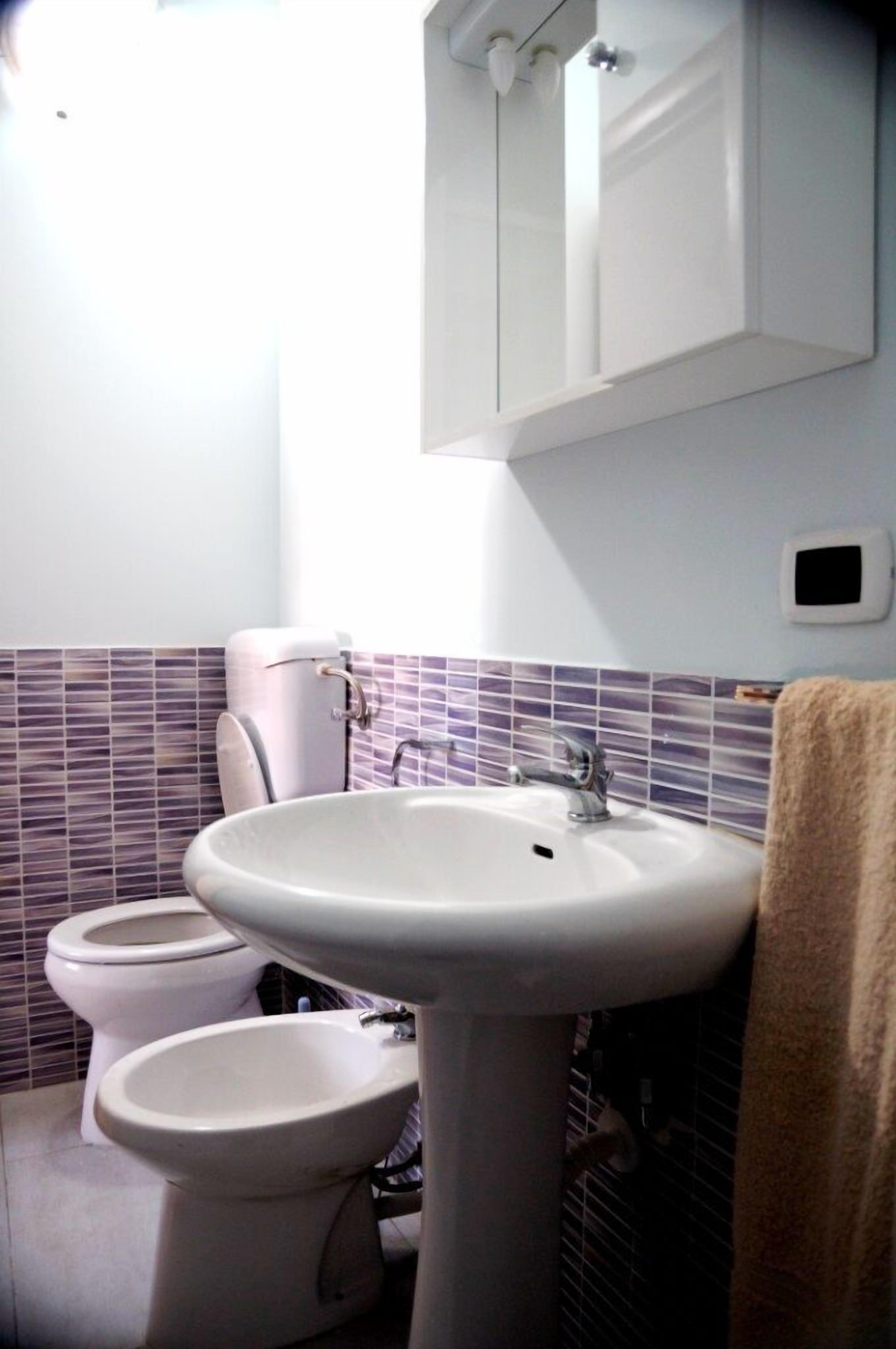 A bathroom with a pedestal sink, a toilet, and a bidet.