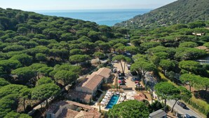 An aerial view of a coastal property with a swimming pool, multiple buildings, and dense greenery. - Hôtel L'Escalet  (Ramatuelle)