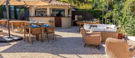 Un espacio al aire libre con mesas, sillas, una barra y una parrilla.