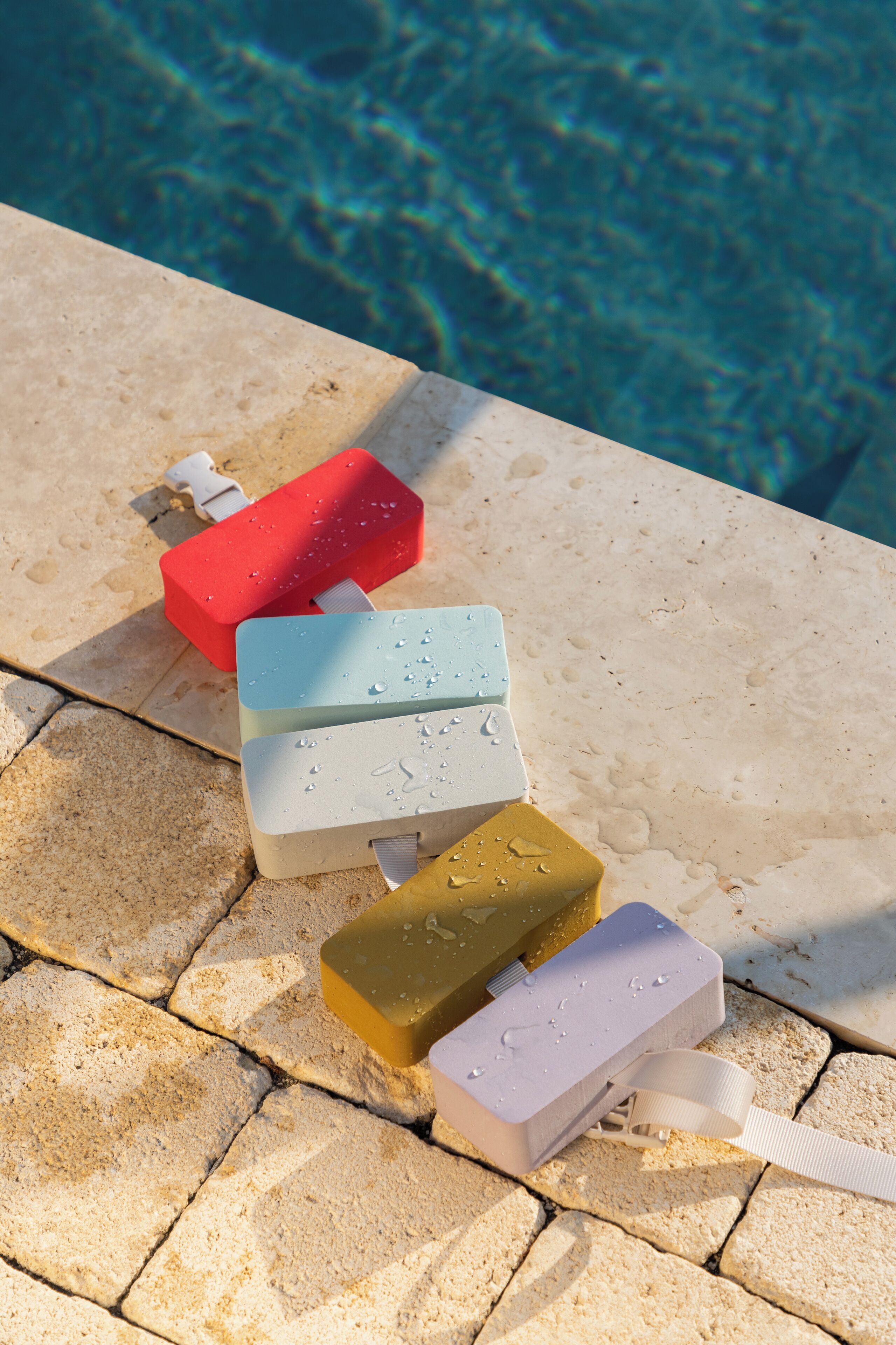 Quatre brosses à dents disposées sur une surface carrelée, près d’une piscine.
