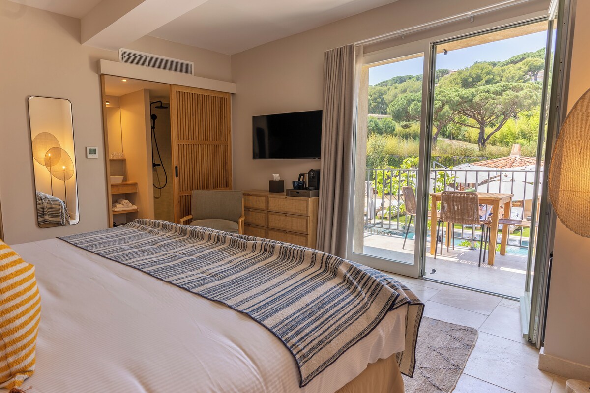 Une chambre d’hôtel dotée d’un grand lit, d’une télévision, d’une salle de bain avec douche et d’un balcon aménagé avec du mobilier d’extérieur.