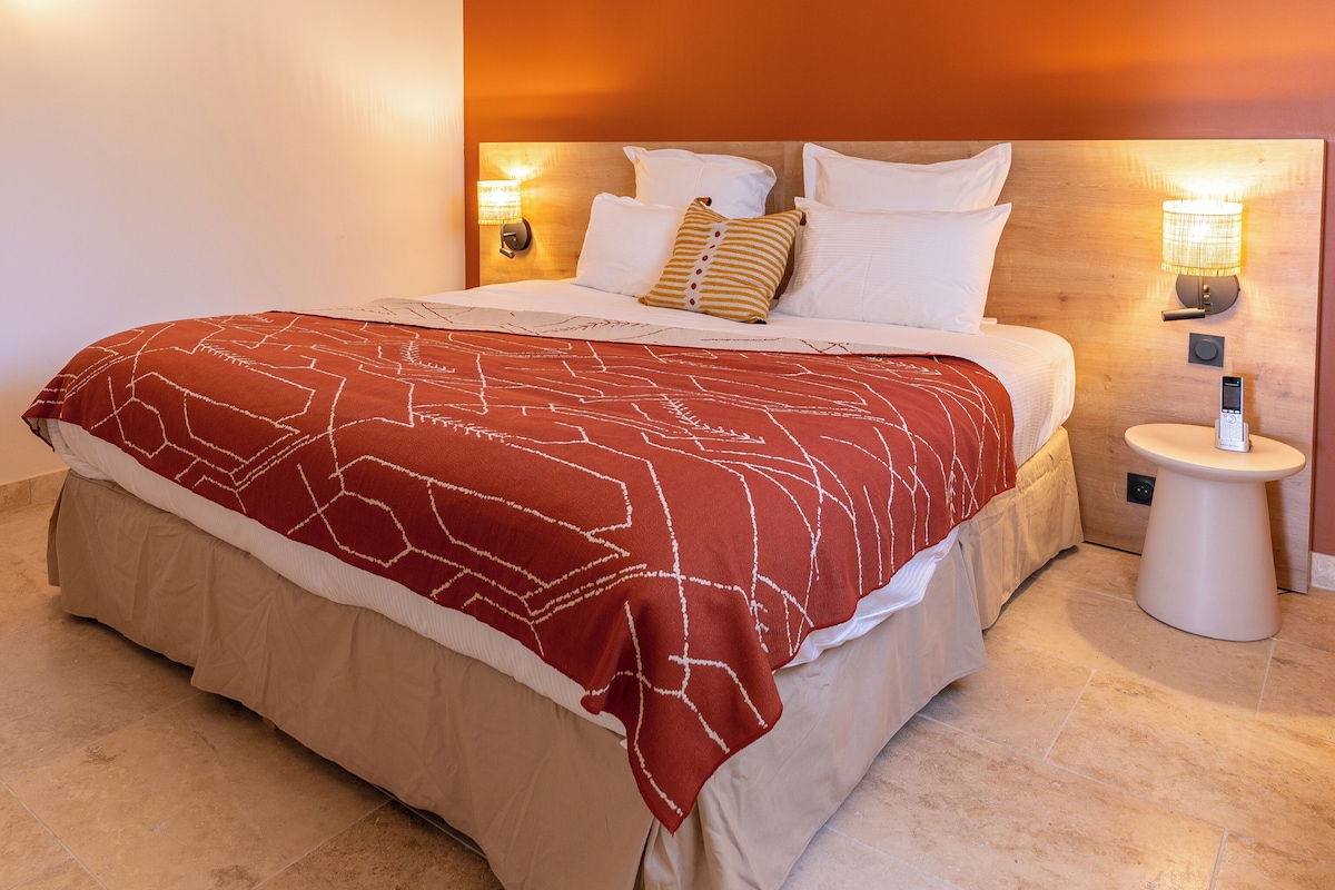 Ein Hotelzimmer mit einem Bett, einem Nachttisch mit Lampe und einer Wandleuchte.