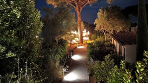 A tree-lined pathway leading to a building with outdoor seating and hanging lights. - Hôtel L'Escalet  (Ramatuelle)