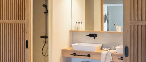 Une salle de bain moderne avec un meuble-lavabo en bois, un grand miroir et un espace douche.