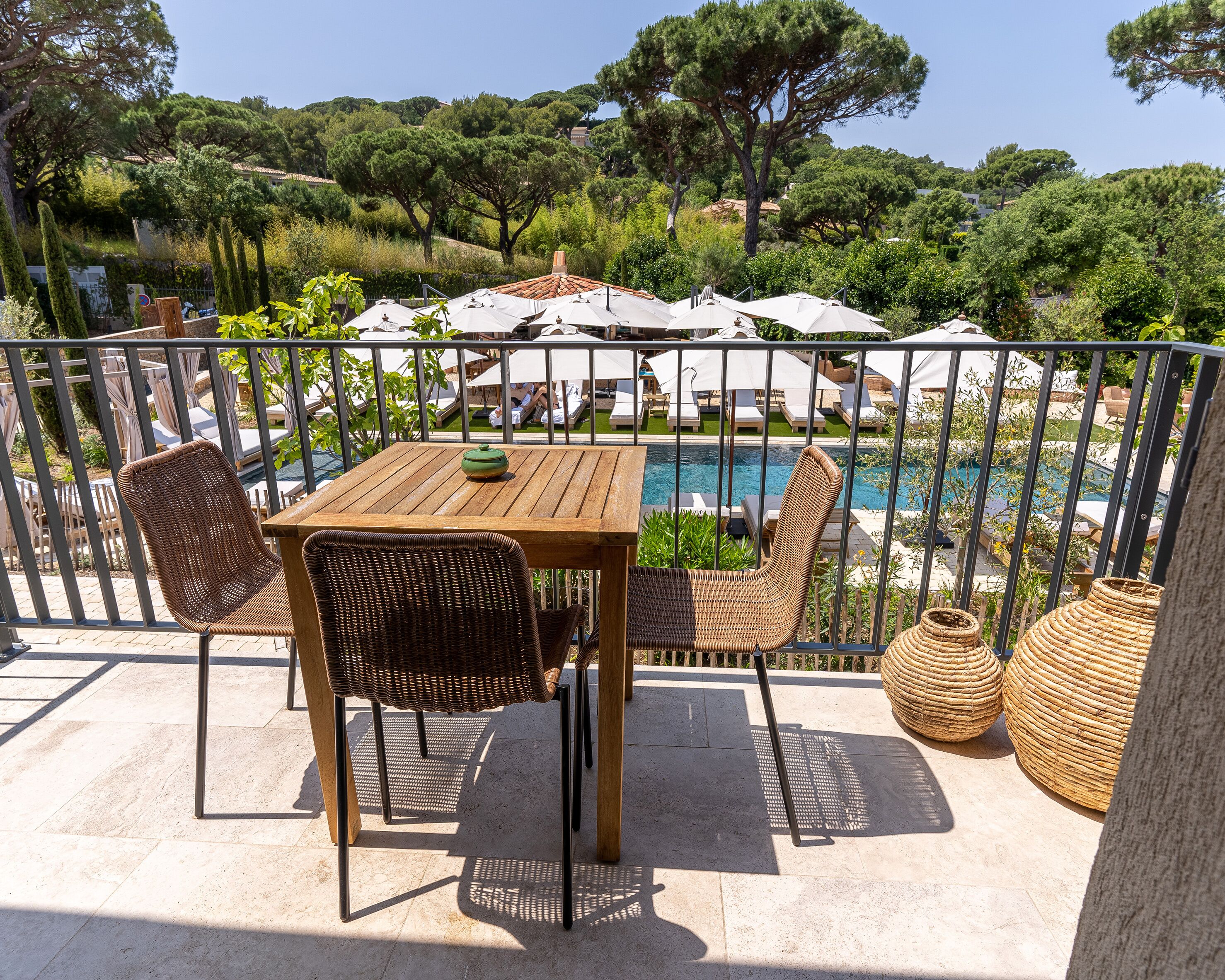 Une terrasse avec une piscine, des meubles en osier et des parasols.