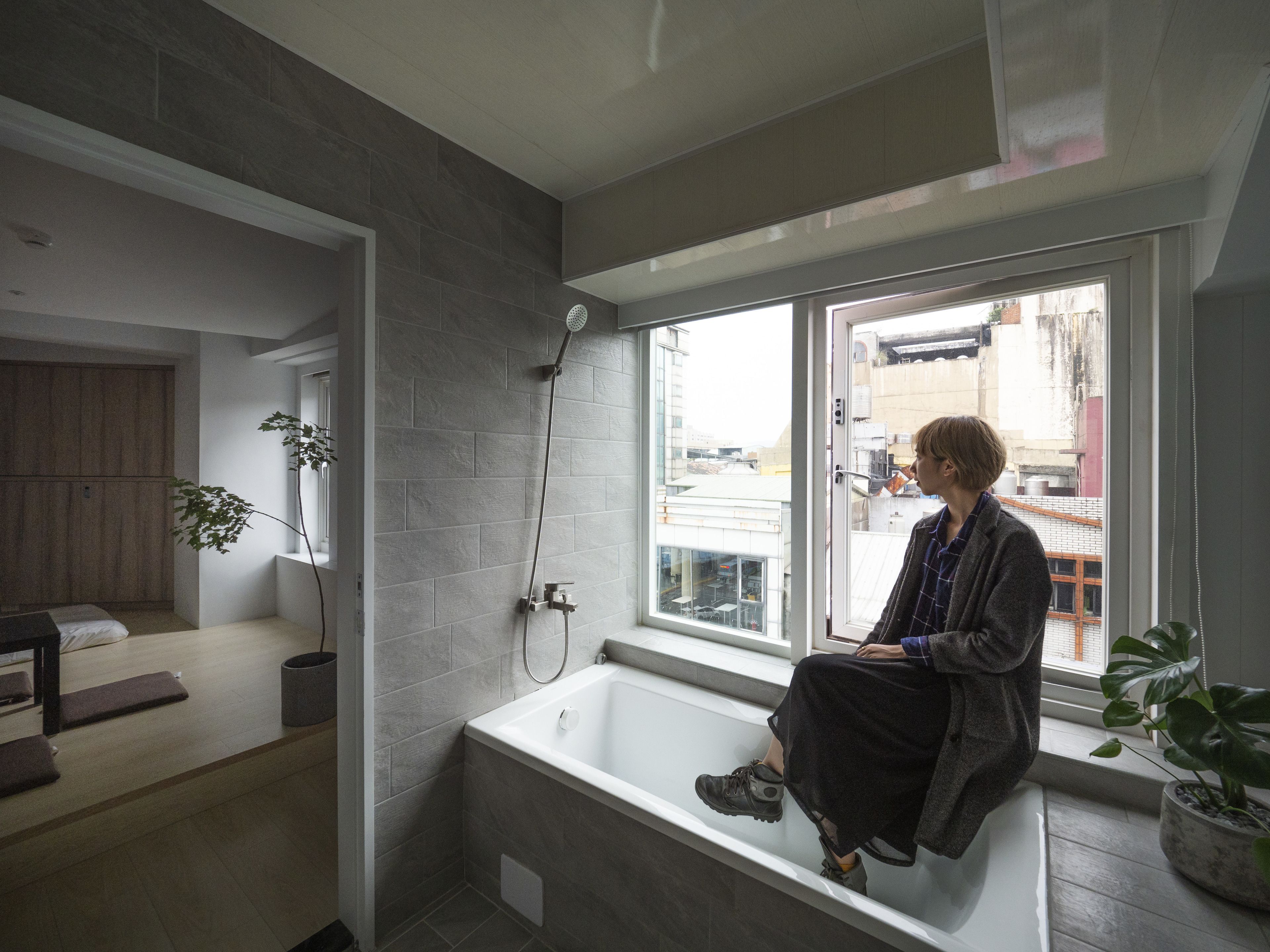 Un baño moderno con bañera, ducha y ventana con vistas a la ciudad.