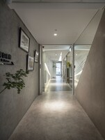 Un pasillo moderno y bien iluminado con un letrero acogedor, cuadros enmarcados y una planta.