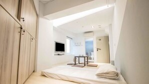 A modern bedroom with a bed, a TV, and a small table with a chair. - LIGHT INN - Hostel (Keelung)