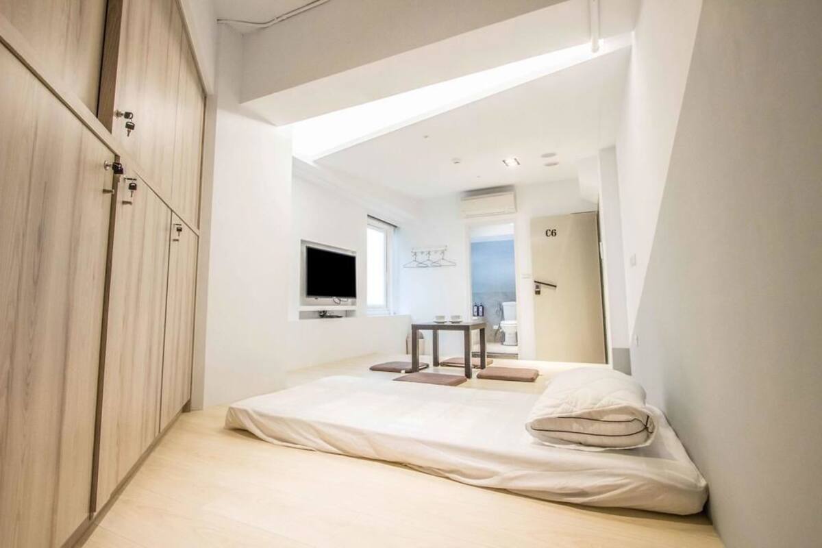 A modern bedroom with a bed, a TV, and a small table with a chair.