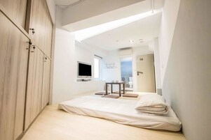 Un dormitorio moderno con una cama, un televisor y una mesita con una silla.