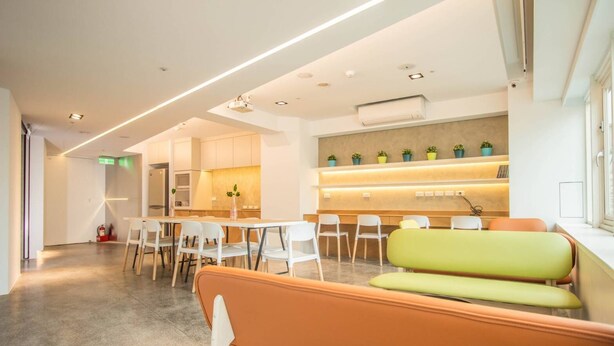 A modern waiting area with a reception desk, seating, and a fire extinguisher. - LIGHT INN - Hostel (Keelung)
