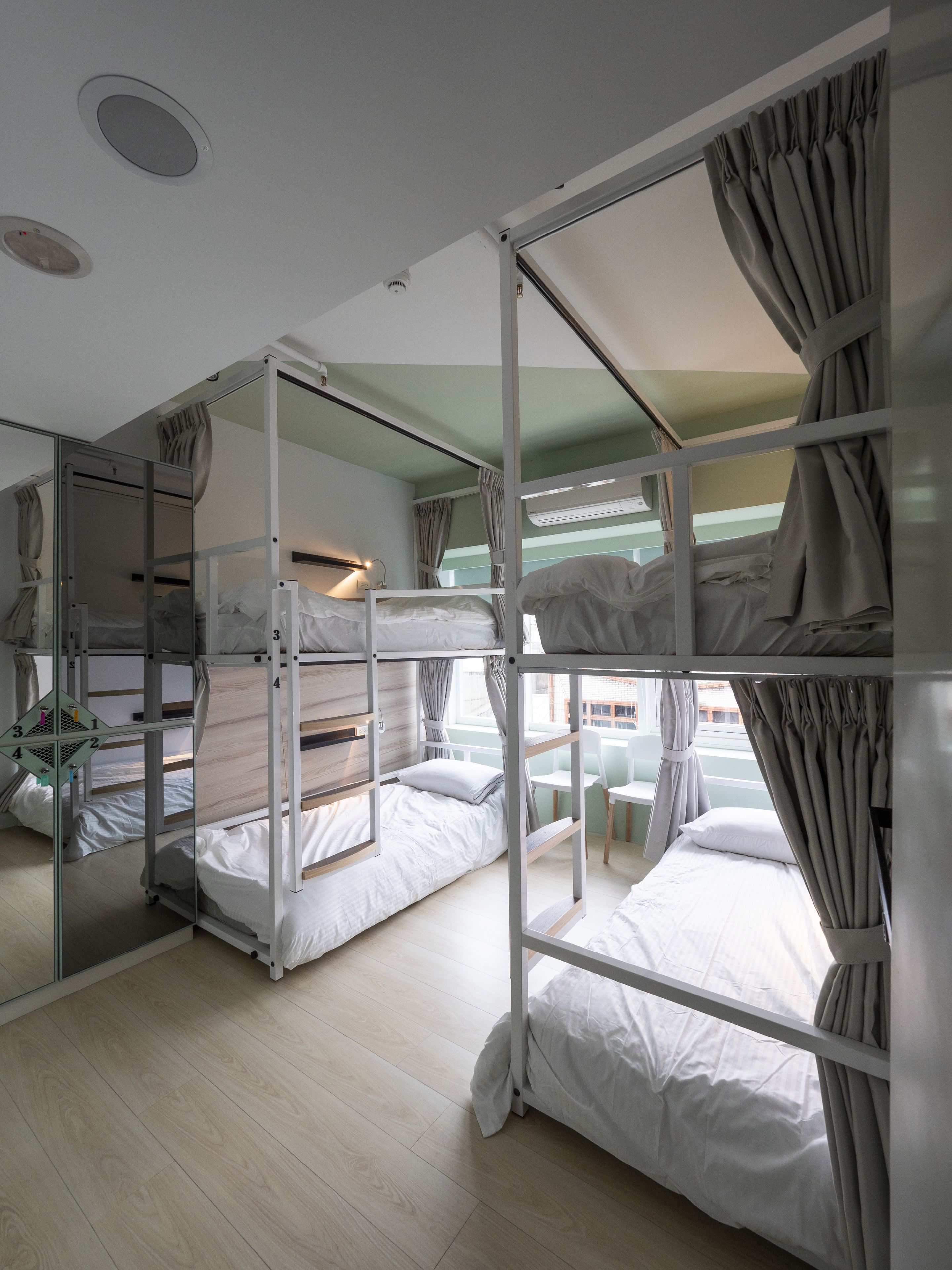 A bunk room with two beds, a mirror, and a window with curtains.