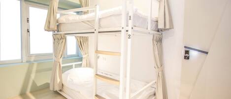 A bunk bed room with a window, curtains, and a door labeled B2.