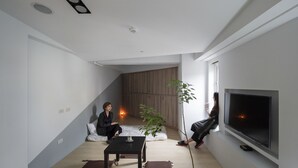 A modern living room with a flat-screen TV, a coffee table, and a potted plant. - LIGHT INN - Hostel (Keelung)