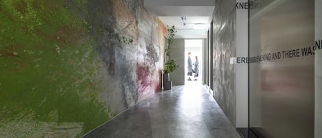 Un pasillo con pared texturizada y una planta en maceta.
