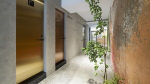 A hallway with a modern design, featuring a plant, a textured wall, and a door with a sign. - LIGHT INN - Hostel (Keelung)