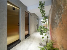Un pasillo de diseño moderno, con una planta, una pared con textura y una puerta con letrero.