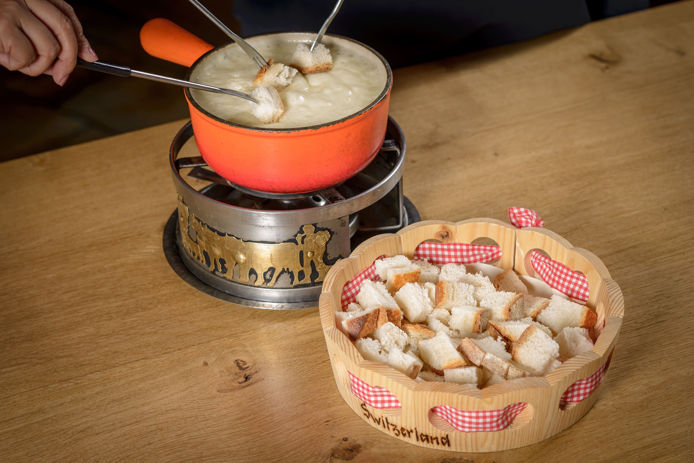 Uma mesa de madeira com uma panela de sopa e uma cesta de pão.