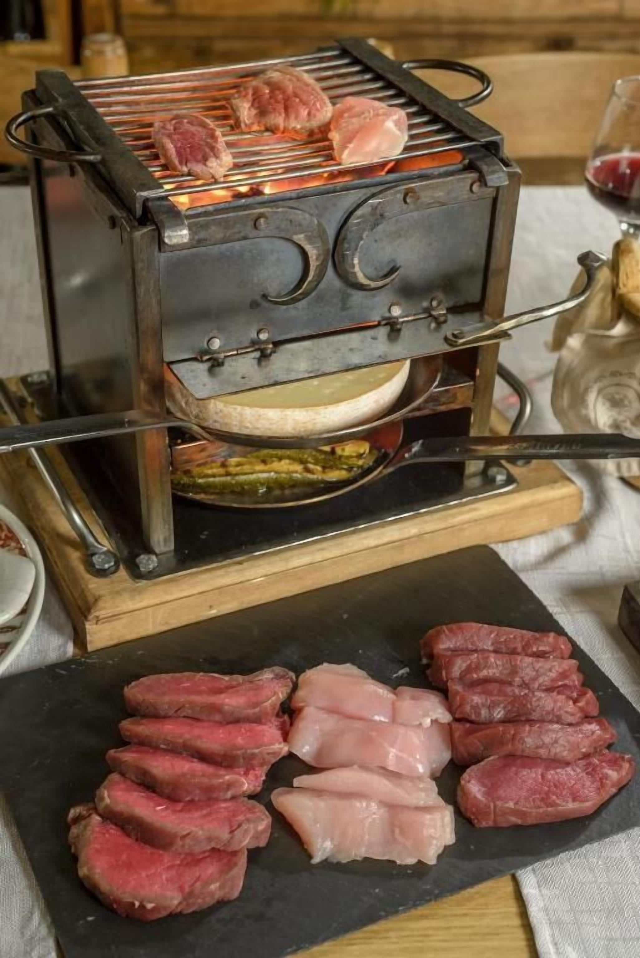 A meat grilling setup with raw and cooked meats on a cutting board.