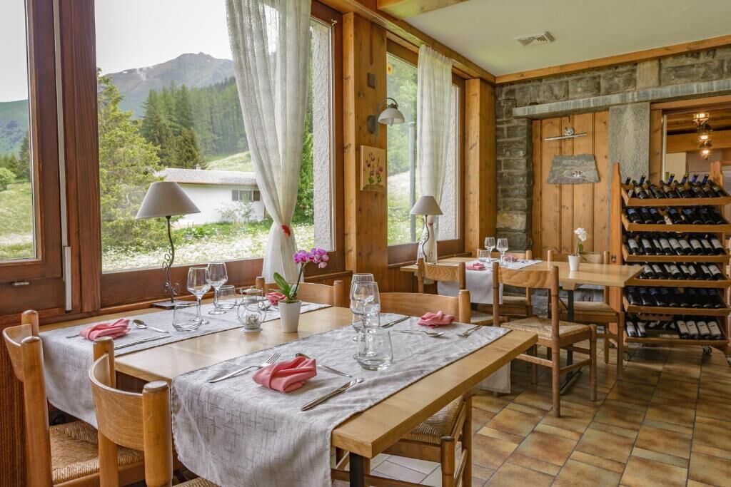 Un espace repas avec des tables et des chaises en bois, un meuble à vin et une vue sur l’extérieur.