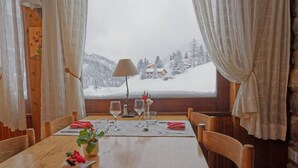 Ein Holztisch mit Blick auf eine verschneite Berglandschaft durch ein Fenster.