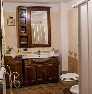 A bathroom with a wooden vanity, a sink, a mirror, and a toilet. - B&B Il Fienile (San Gimignano)
