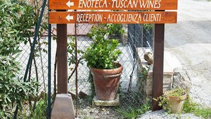 A wooden sign with directional arrows pointing to various hotel sections including B&B, rooms, enoteca, and reception. - B&B Il Fienile (San Gimignano)