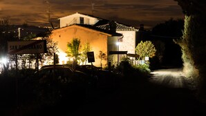 A building with a sign reading "SAN GIMIGNANO" at night, surrounded by vegetation and a dimly lit road. - B&B Il Fienile (San Gimignano)