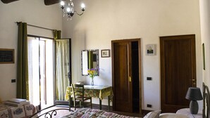 A bedroom with a bed, a desk with a chair, a mirror, and two doors. - B&B Il Fienile (San Gimignano)