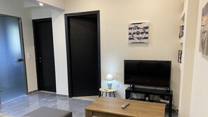 Una sala de estar moderna con un sofá, una mesa de centro, un televisor y una lámpara.