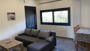 Una sala moderna con un sofá seccional, una mesa de madera, una mesa de comedor con sillas, un ventanal y una puerta.