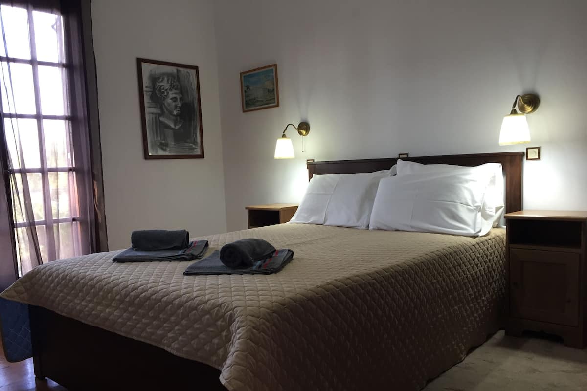 A neatly made bed with a quilted cover, two bedside lamps, and a nightstand with a lamp.