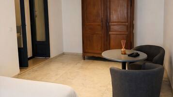 Una habitación con una cama, una mesa redonda con dos sillas, un armario de madera y una lámpara en el techo.